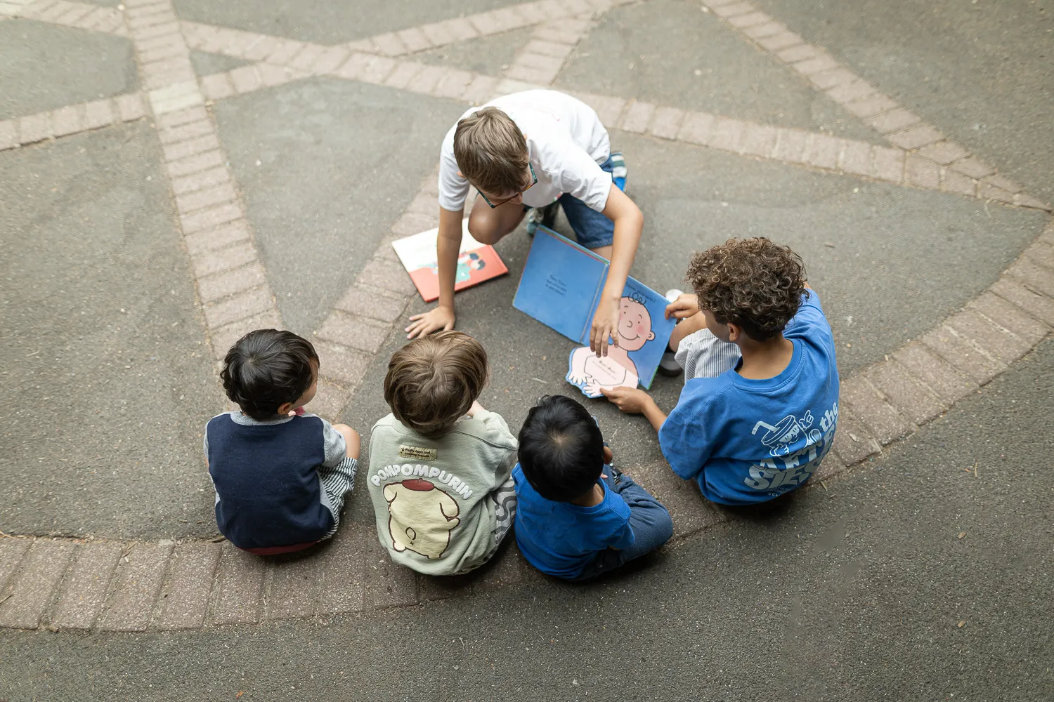 Ecoliers dans une cour d'école assis par terre en train de jouer
